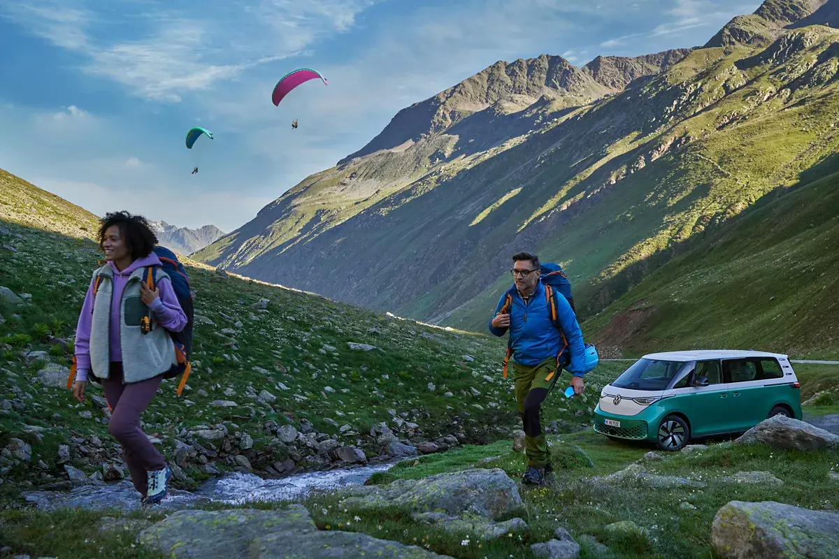 zwei Personen gehen wandern, dahinter steht ein grüner ID Buzz