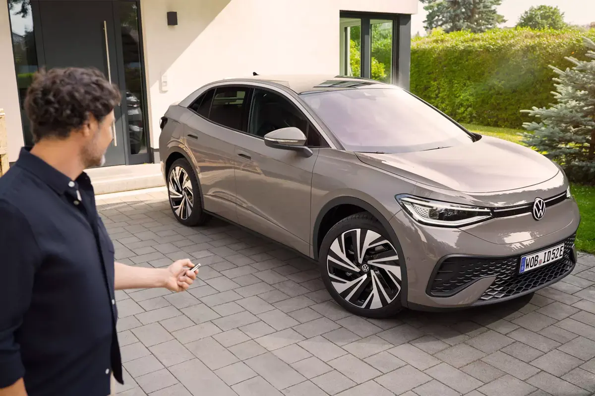 VW ID5 vor einem Haus, daneben ist ein Mann