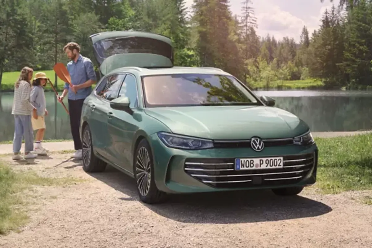 Grüner VW Passat vor einem See, daneben steht ein Mann mit zwei Kindern