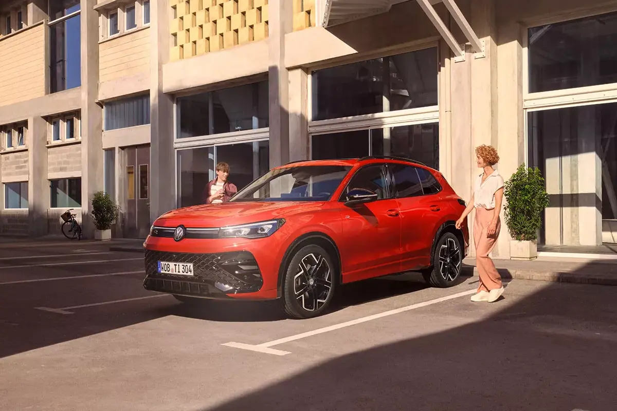 Roter Tiguan am Parkplatz, daneben ist eine Frau