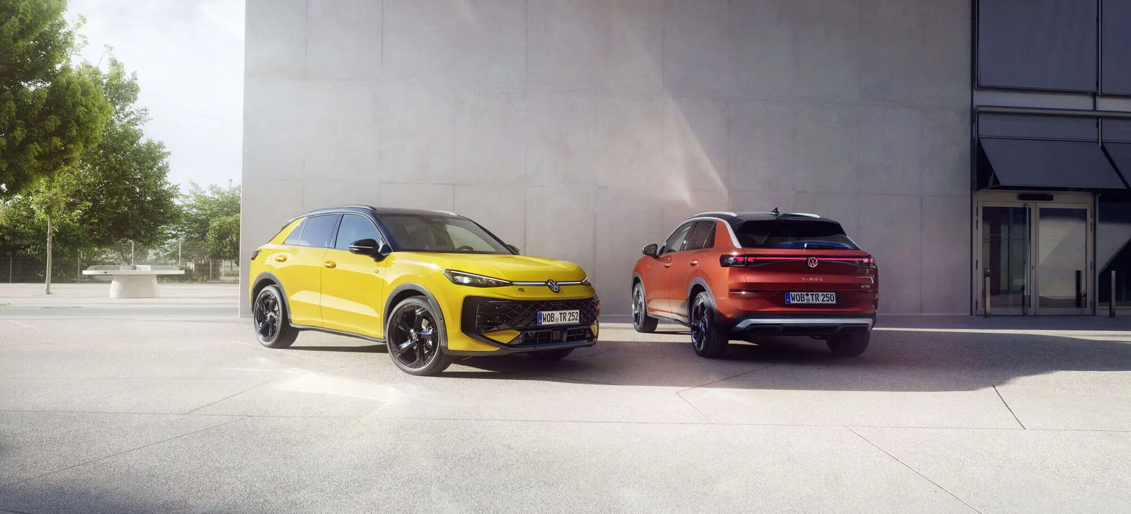 ein gelber T-Roc von vorne steht neben einem roten T-Roc von hinten